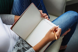 Woman writing in hardcover journal